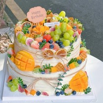 Torta di compleanno a forma rotonda a doppio strato con crema di latte e frutta mista